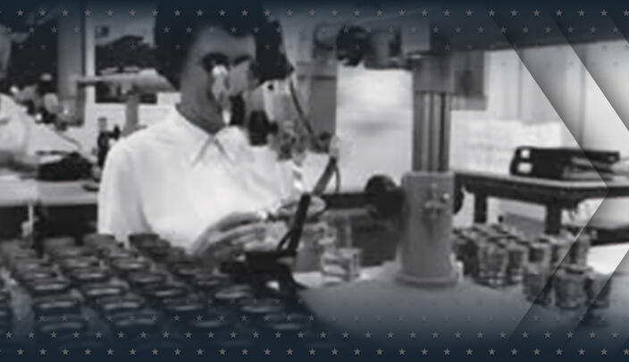 Woman looks through microscope at laboratory