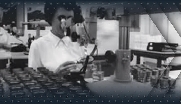 Woman looks through microscope at laboratory
