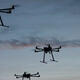 Multiple UAV drone copters flying with sunset sky behind them. Thumbnail image.