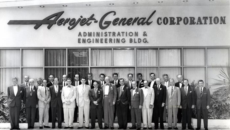 A black and white photo of a group of people in front of a building