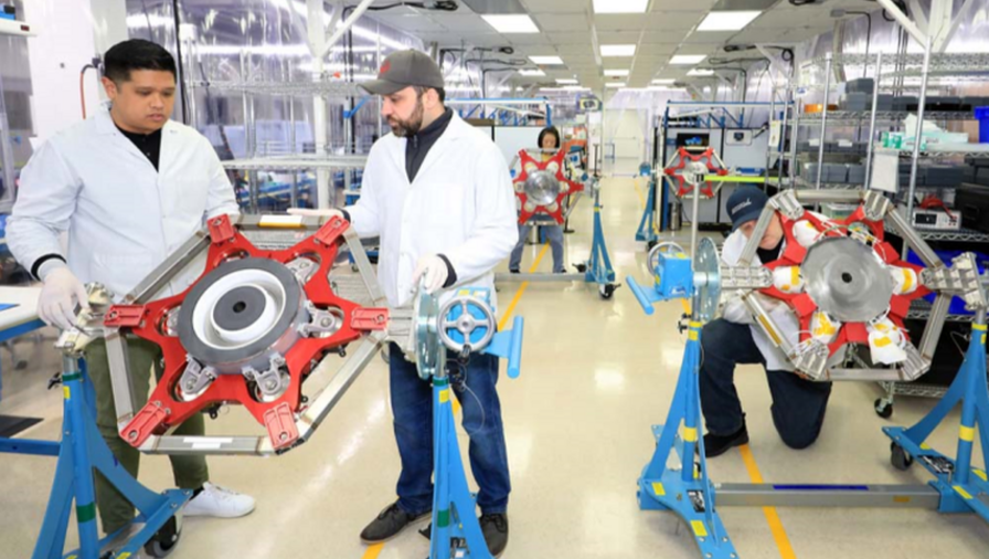 Employees inspect a part in a facility