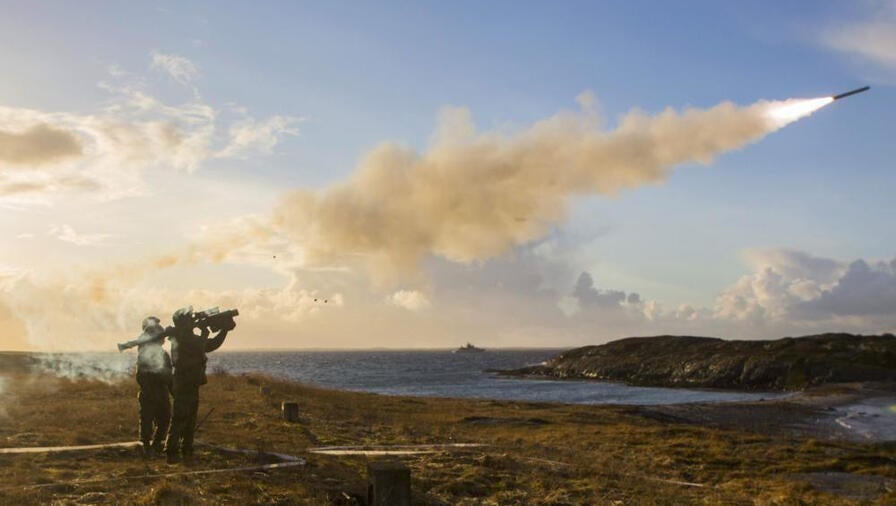 A soldier fires a missile from a shoulder launcher in a field