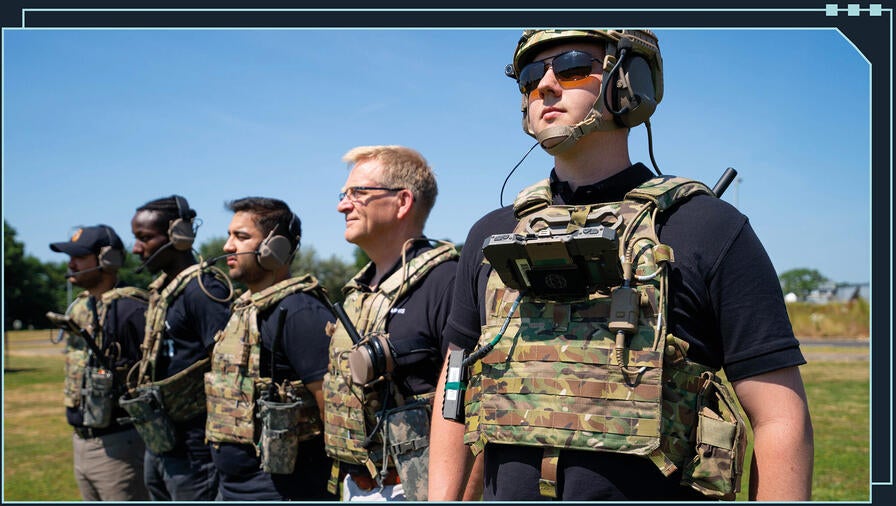row of soldiers wearing camo vests mounted with radios and other EW equipment