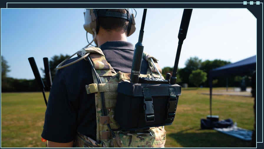 Man standing in a field wearing camo vest mounted with corvus ICN