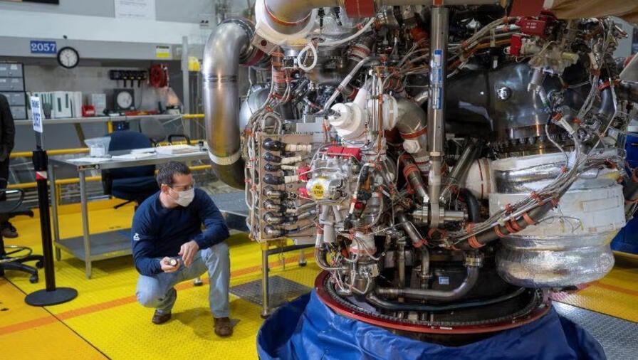 An Aerojet Rocketdyne engineer examines RS-25 engine