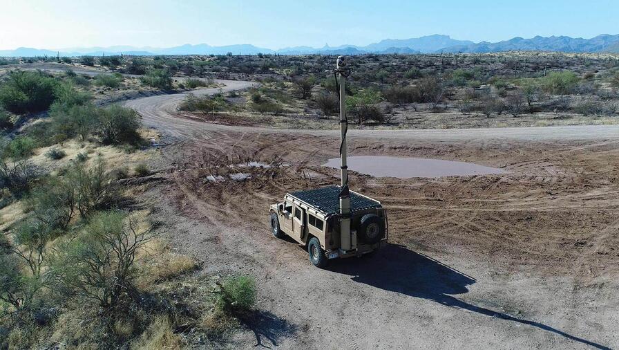 Humvee in the distance with a surveillance mast deployed