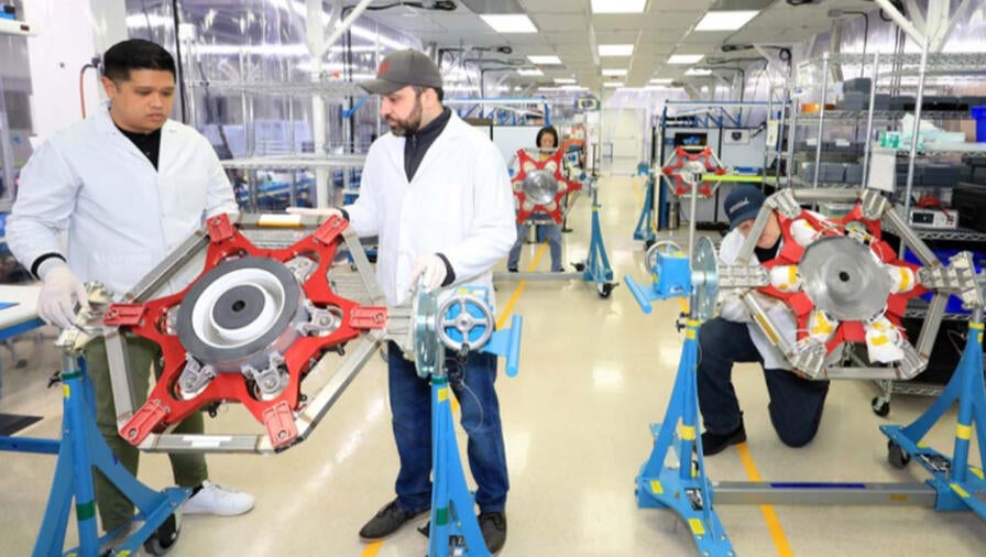 Employees inspect a part in a facility
